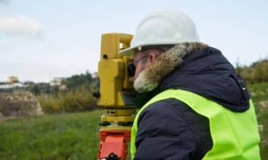 Licensed land surveyor conducting a boundary line survey with professional equipment on a residential property