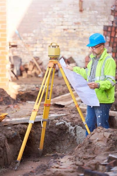 Land surveyor reviewing blueprints for elevation certificate - ALTA SURVEY Tennessee Licensed land surveyor reviewing blueprints and elevation data while preparing an elevation certificate on a construction site