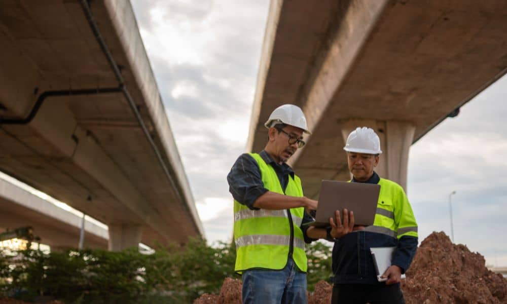 Civil engineering firms reviewing bridge construction plans on site to ensure proper quality control and safety