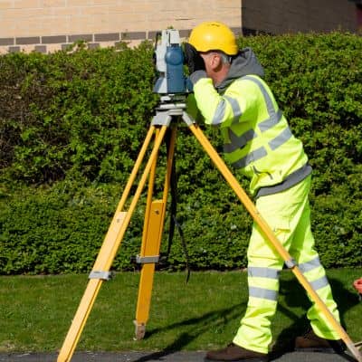 Field surveyor using a total station for measurements supporting an ALTA land survey