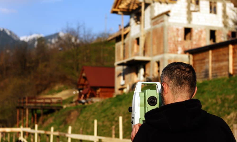 Surveyor measuring residential building height for a FEMA elevation certificate after storm damage review