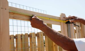 Measuring fence backyard - ALTA SURVEY Tennessee Person measuring fence line in backyard before a land survey for fence installation