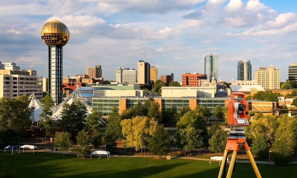 alta survey knoxville tn - ALTA SURVEY Tennessee Theodolite on tripod in front of downtown Knoxville, TN skyline during golden hour, highlighting urban land surveying for ALTA survey purposes.