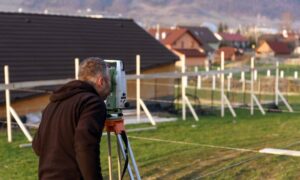 Surveyor using a total station to conduct a boundary survey on a residential property