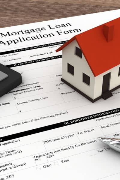 Mortgage loan application form with house model, calculator, and pen showing how an elevation certificate affects home financing and insurance
