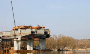 Ongoing riverfront construction project with crane and bridge work showing the need for construction surveys