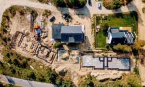 Drone surveying capturing an aerial view of a construction site with visible building foundations and land grading for redevelopment