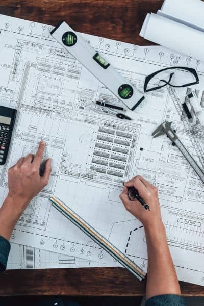 Engineer reviewing technical site plan drawing - ALTA SURVEY Tennessee Close-up of engineer working on detailed site plan with helmets and tools on drafting table