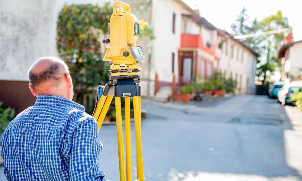 Licensed surveyor measuring a home’s elevation for an elevation certificate after a storm review