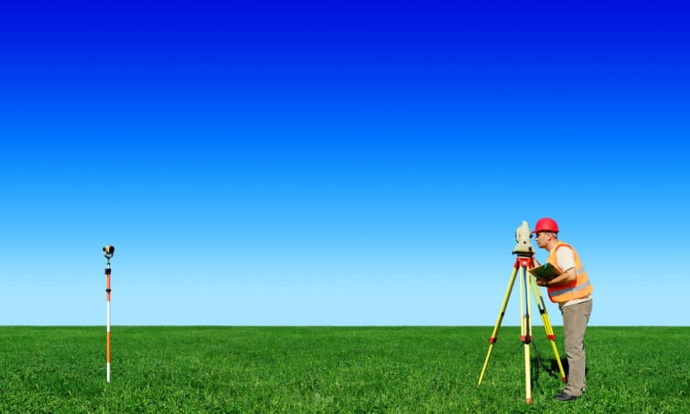 Land boundary survey field measurement - ALTA SURVEY Tennessee Cadastral surveyor using surveying equipment to measure and verify property lines in an open field