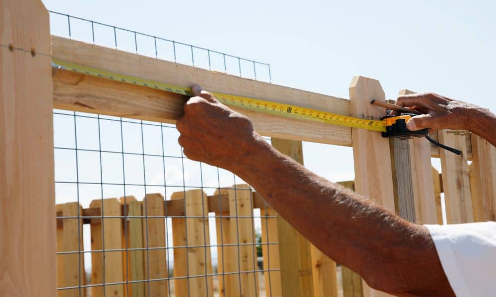 Measuring fence backyard - ALTA SURVEY Tennessee Person measuring fence line in backyard before a land survey for fence installation
