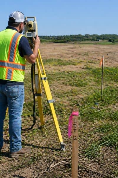 Land surveyor using equipment to measure property boundaries, showing how an ALTA survey verifies land conditions before purchase