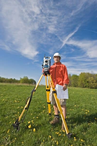 Surveyor using measuring equipment in an open field during a property boundary survey