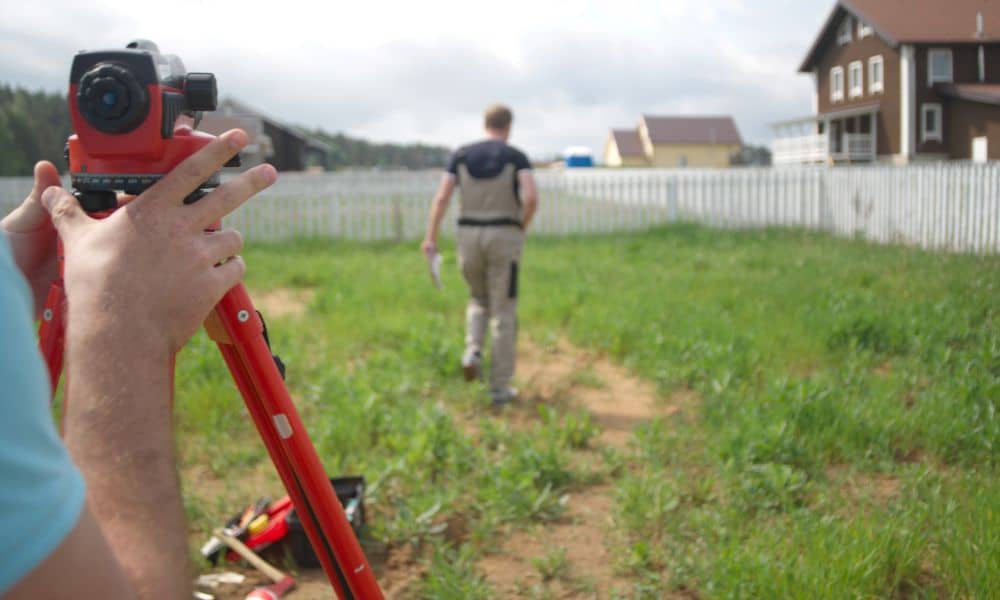 Survey team measuring a residential property near a fence before a Nashville home sale for homeowners seeking survey companies near me